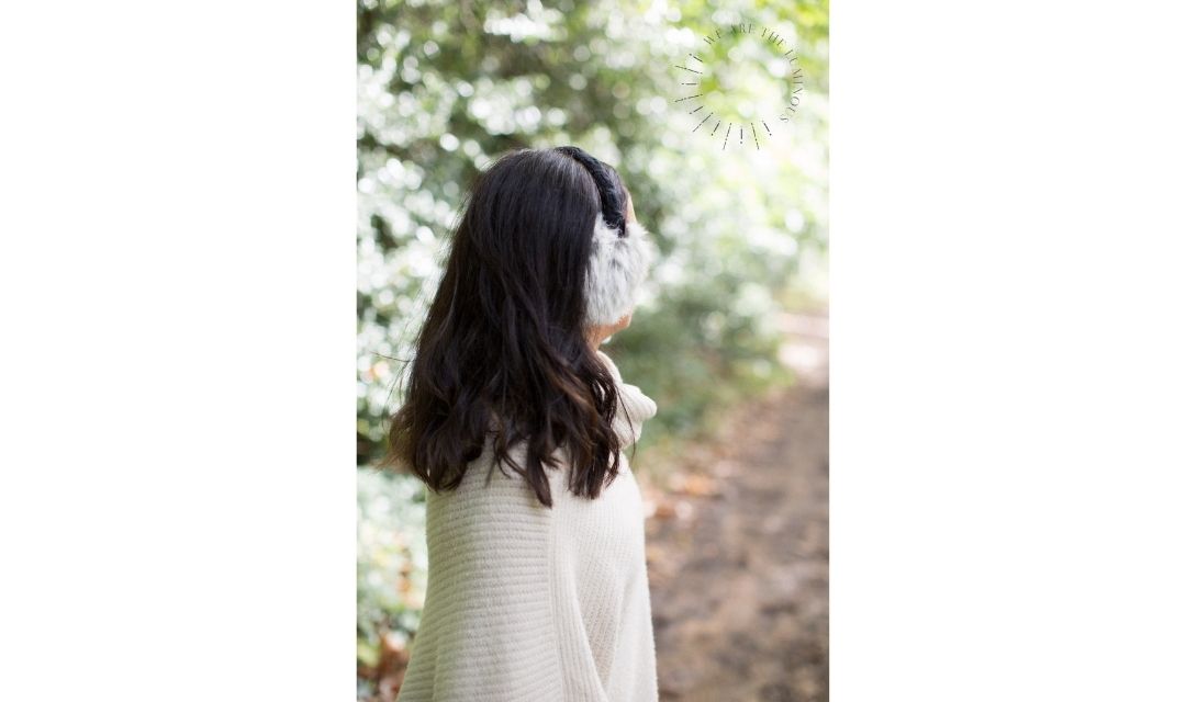 lady wearing ear muffs in the woods
