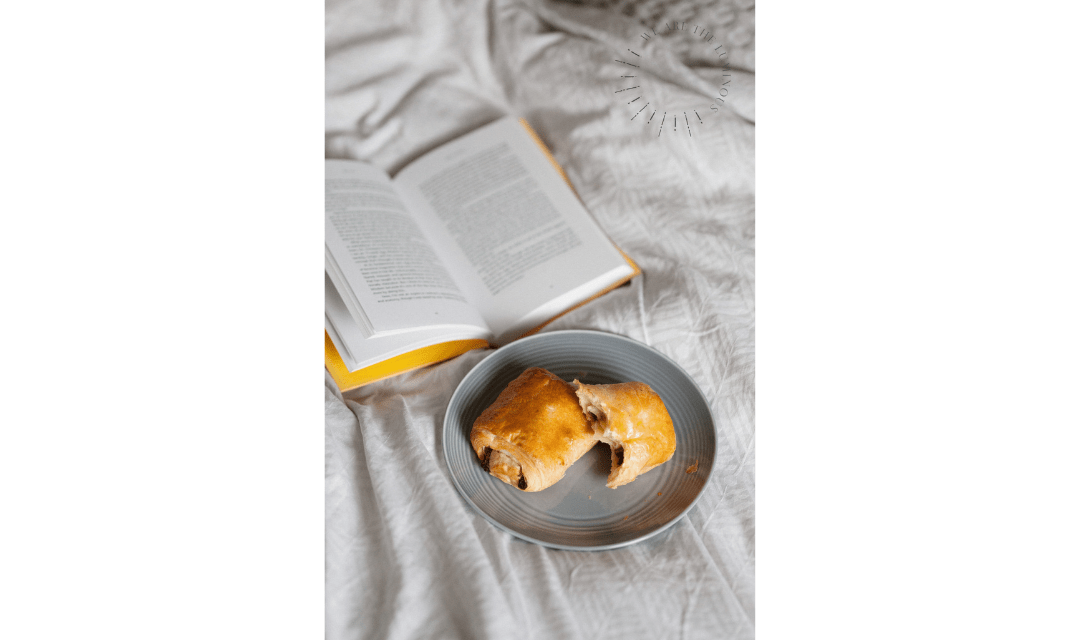 croissant and book in bed stock image
